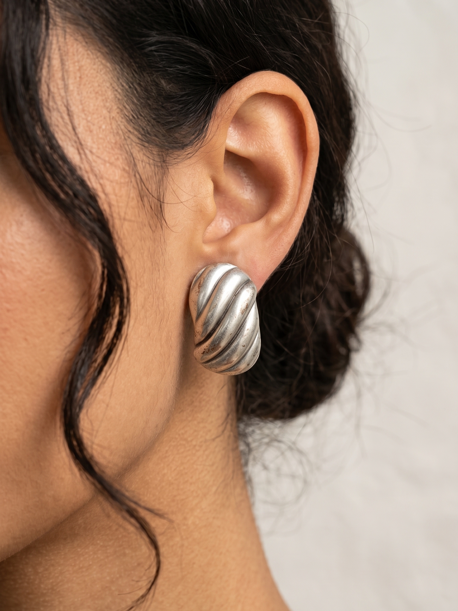 گوشواره ورشو پافی حجم‌دار طرح حلزونی نقره‌ای روی گوش مدل